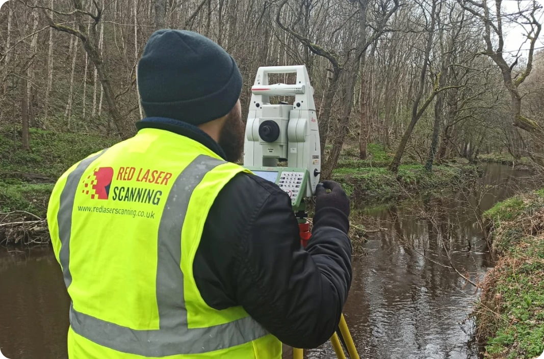Our expert conducts a topographic survey near a riverbank, using a total station to capture accurate landscape measurements