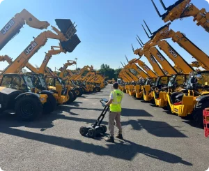 Technician using GPR equipment for geospatial survey among construction vehicles